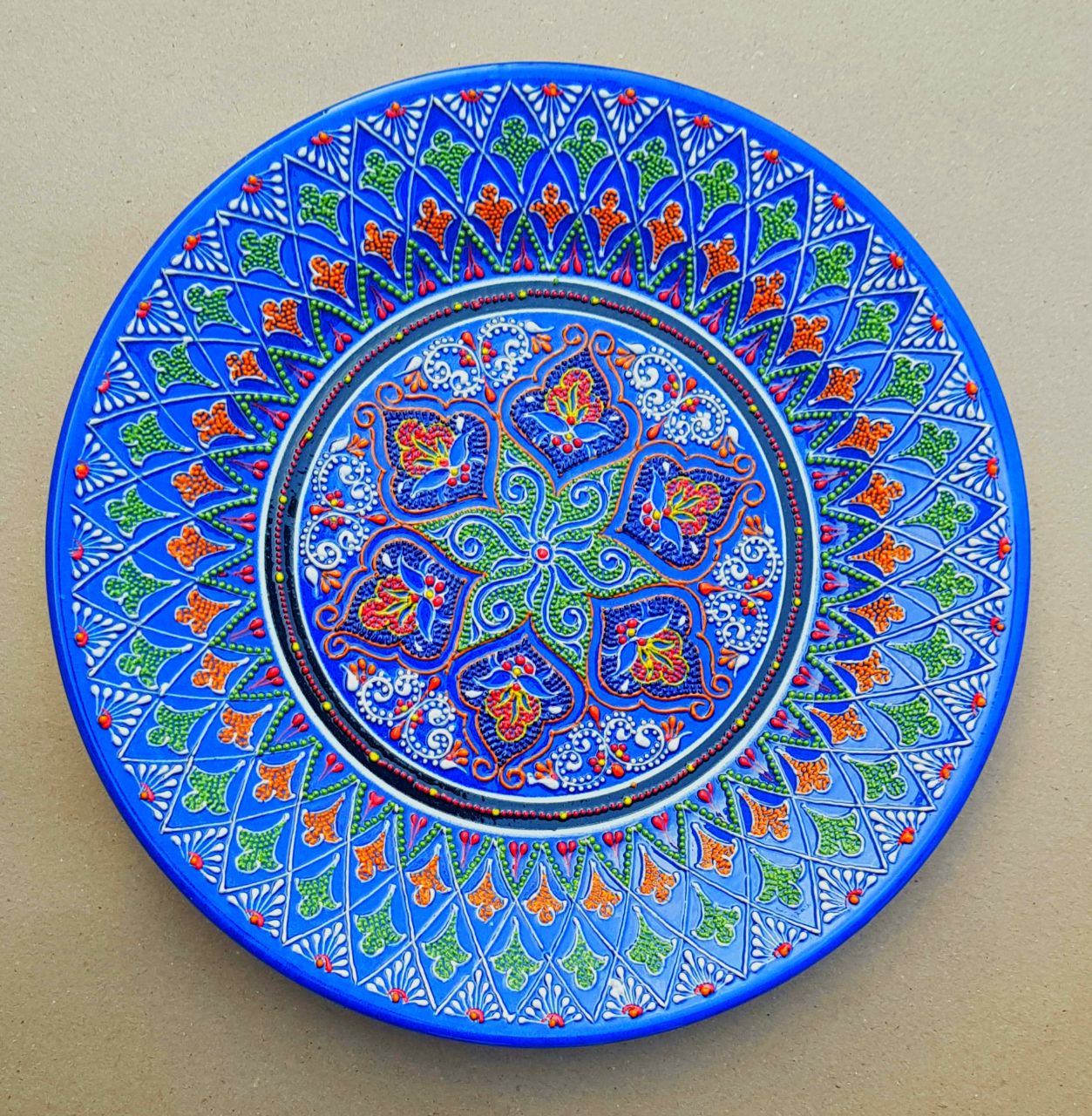 Cobalt-blue ceramic plate with a raised floral medallion and radiating ornament
